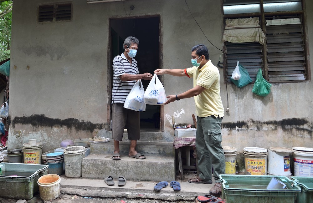 Food Aid representatives give out the donated food parcels to their beneficiaries. — Picture courtesy of Tesco Malaysia. 