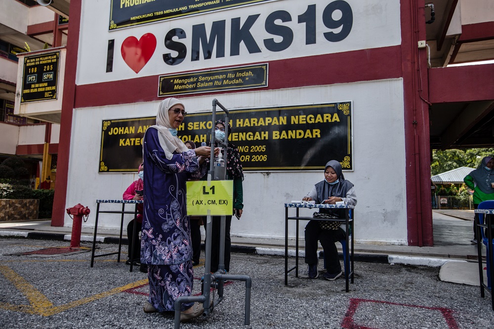 A teacher demonstrates the proper use of a foot pedal-operated hand sanitiser station Sekolah Menengah Kebangsaan (SMK) Seksyen 19 in Shah Alam June 23, 2020. u00e2u20acu201d Picture by Firdaus Latif 