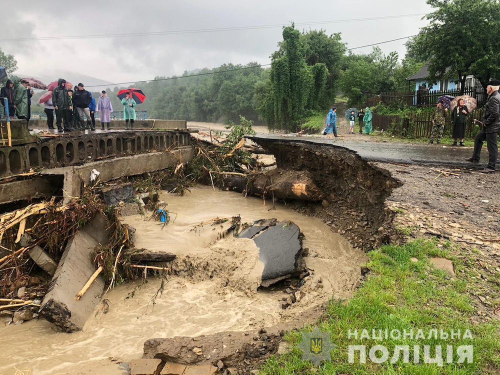 Local residents stand next to a road destroyed by flood in Ivano-Frankivsk region, Ukraine, in this handout picture released by National Police of Ukraine on June 23, 2020. u00e2u20acu201d Reuters pic