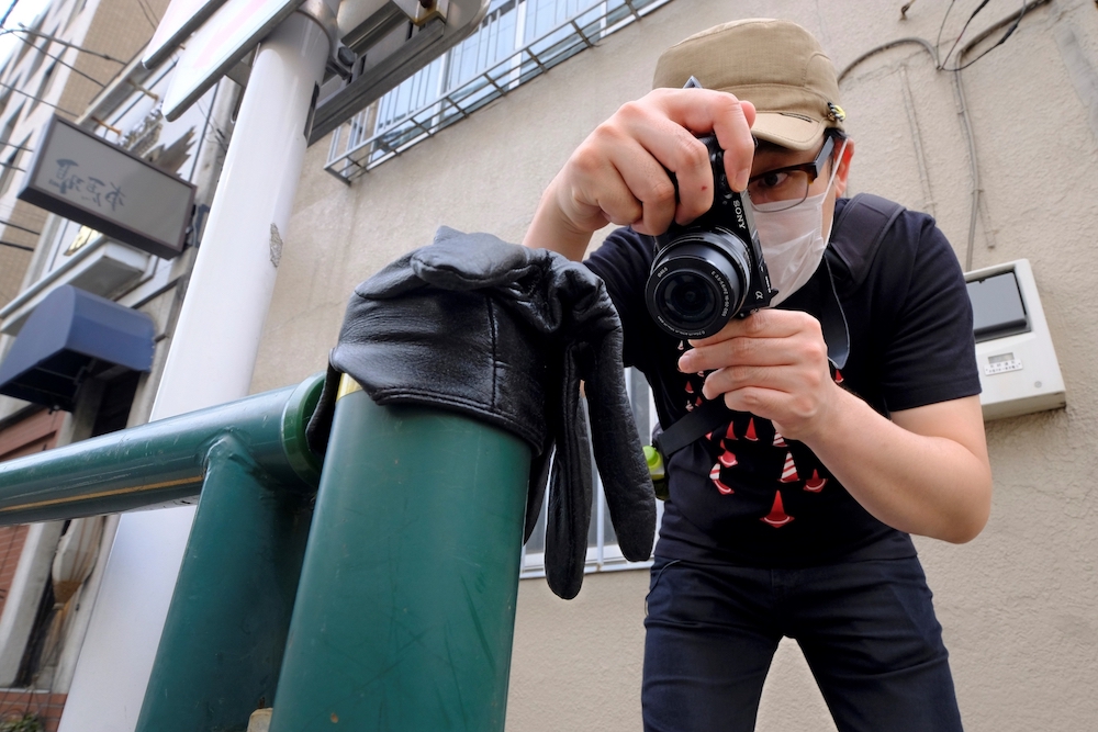 Japanese photographer Koji Ishii taking pictures of a lost glove on a pole beside the road in Tokyo. u00e2u20acu201d AFP pic