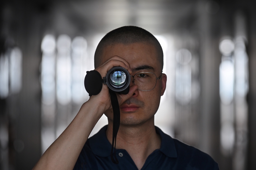 Dai Pengjun, a private detective who investigates suspected infidelities, posing with a prismatic scope he uses for work in Shanghai. u00e2u20acu201d AFP pic