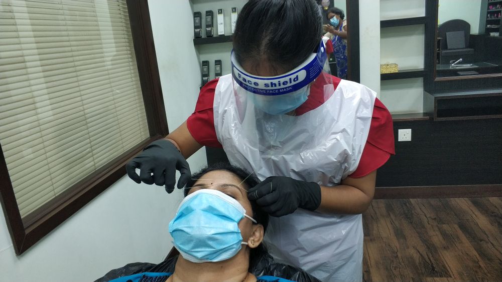 A beautician at Akshada Beauty, Bridal and Boutique demonstrates her threading skills on Sarojini. u00e2u20acu201d Picture by Yiswaree Palansamy