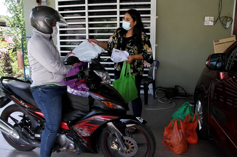Tukang jahit Saidatul Emma Ahmad Tohar, 29, (kanan) menggunakan perkhidmatan penghantaran untuk menghantar pakaian baju raya telah siap dijahit kepada pelanggan sepanjang tempoh Perintah Kawalan Pergerakan (PKP) di Ipoh 5 Mei, 2020. u00e2u20acu201d Foto Bernama
