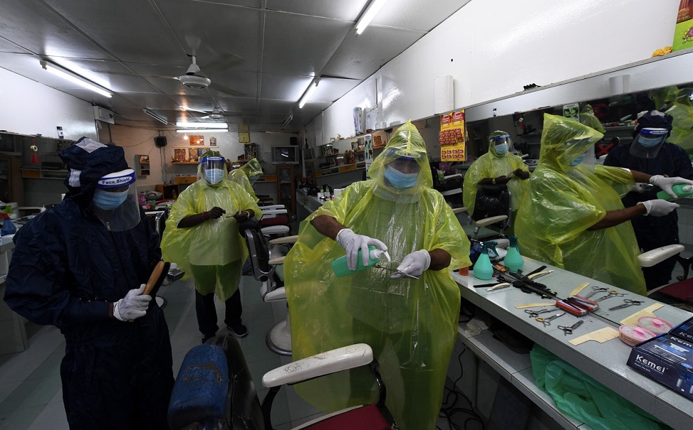 Barbers in protective gear are seen disinfecting tools used in their shop at Jalan Tan Sri Teh Ewe Lim in George Town June 9, 2020. u00e2u20acu201d Bernama pic