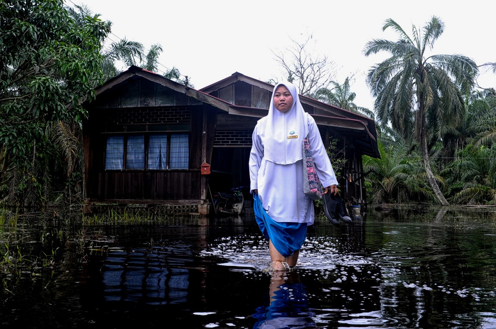 Siti Noraini Matsuki of Sekolah Menengah Kebangsaan (SMK) Penghulu Saat wades through flood water as she makes her way to school, at Kampung Parit Pulai, Parit Sulong June 24, 2020. u00e2u20acu201d Bernama pic