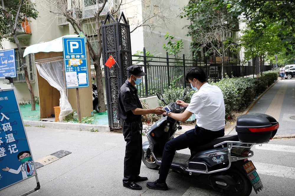 A security guard takes body temperature measurement of a man at an entrance to a residential compound following new cases of coronavirus disease infections in Beijing June 17, 2020. ― Reuters pic
