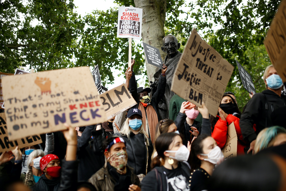 Demonstrators wearing protective face masks and face coverings hold placards during a Black Lives Matter protest in Parliament Square, following the death of George Floyd who died in police custody in Minneapolis, London, Britain, June 6, 2020. u00e2u20acu201d Reuter