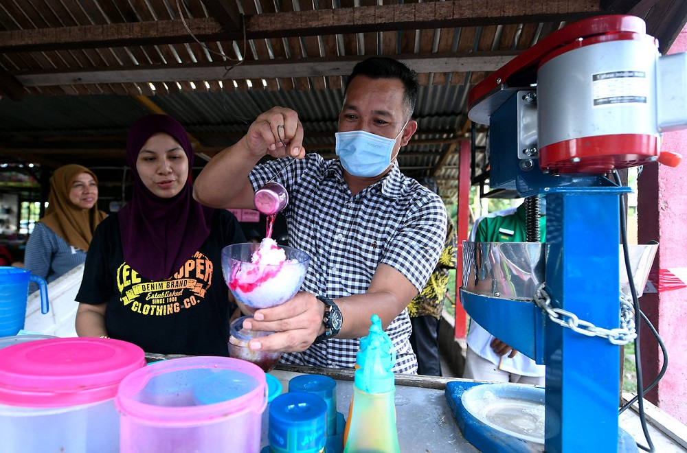Barisan Nasional candidate Mohd Sharim Md Zain is seen making u00e2u20acu02dcice kacangu00e2u20acu2122 at a stall as he campaigns at Bandar Dara Felda Chini in Pekan June 22, 2020. u00e2u20acu2022 Bernama pic