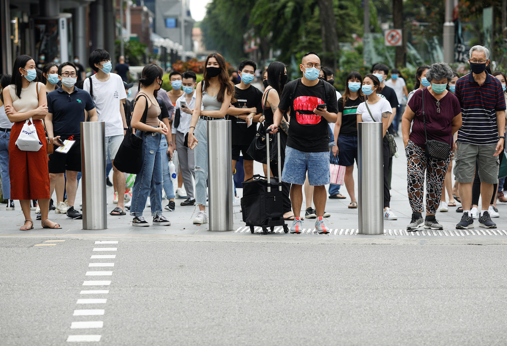 People wait to cross a street at the shopping district of Orchard Road as the city state reopens the economy, amid the coronavirus disease outbreak, inSingapore June 19, 2020. u00e2u20acu2022 Reuters picnn