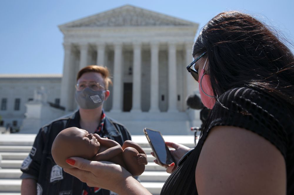 An anti-abortion activist, holding a replica of a human foetus, reads about a US Supreme Court abortion ruling as demonstrators gather outside the court in Washington DC, June 29, 2020. u00e2u20acu201d Reuters pic