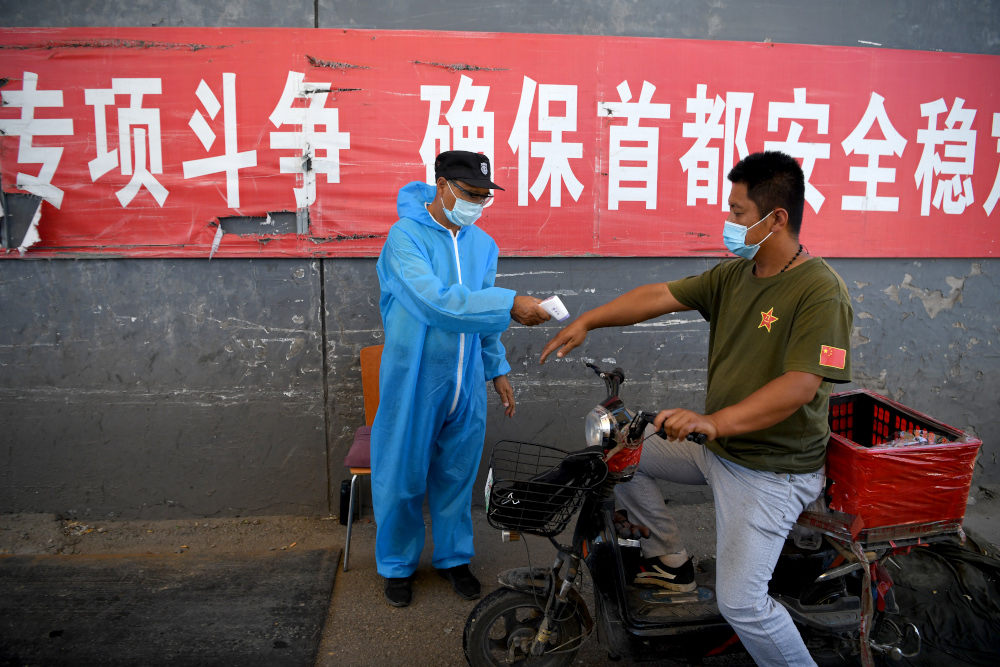 A security personnel checks the temperature of a man on a motorcycle entering the Xinfadi market in Beijing June 14, 2020. u00e2u20acu201d AFP pic 