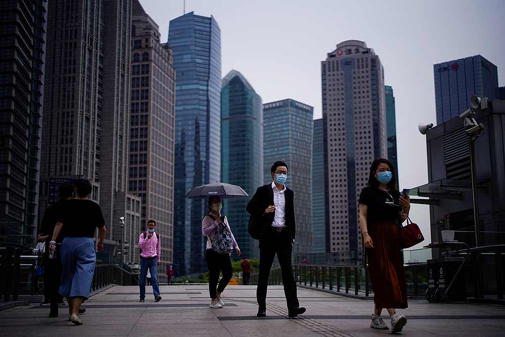 People wearing protective face masks walk past office buildings in Lujiazui financial district in Pudong, in Shanghai, following the Covid-19 outbreak, China June 4, 2020. u00e2u20acu201d Reuters pic