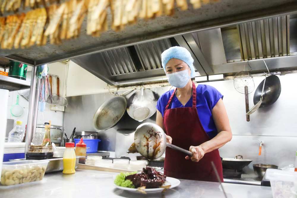 Jennifer Tee cooking up a storm in her kitchen while observing hygiene practices. — Picture by Choo Choy May