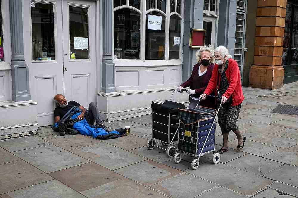 Women wearing face masks and pushing shopping bags on wheels walk past a homeless man a day before all shops were permitted to re open as the Covid-19 lockdown eases in London, Britain June 14, 2020. u00e2u20acu201d Reuters pic