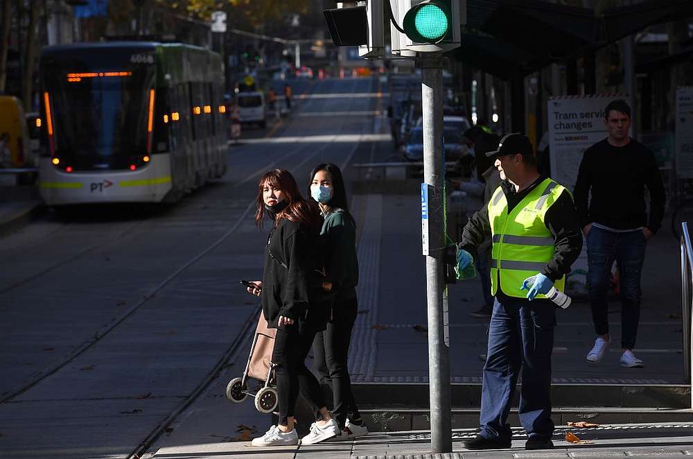 A cleaner (right) wipes down a pole in Melbourne's central business district as more Australians return to the city centre June 17, 2020. u00e2u20acu201d AFP pic