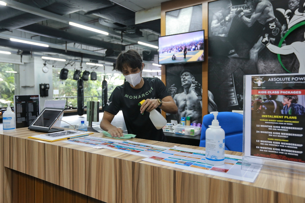 Mohammad Faisal Wilkinson from the Monarchy MMA gym disinfects the reception counter on the first day of operation June 15, 2020. — Picture by Ahmad Zamzahuri