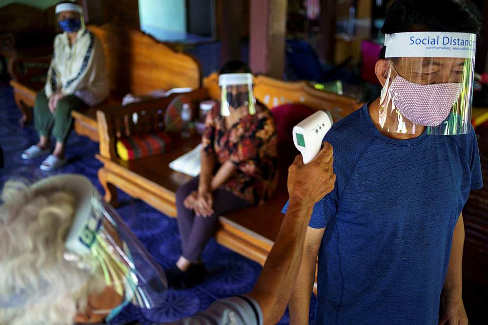 Village health volunteer Surin Makradee, 77, checks the temperature of a man under quarantine during visits to houses to prevent the spread of Covid-19 in Ang Thong province, Thailand, May 27, 2020. u00e2u20acu201d Reuters pic