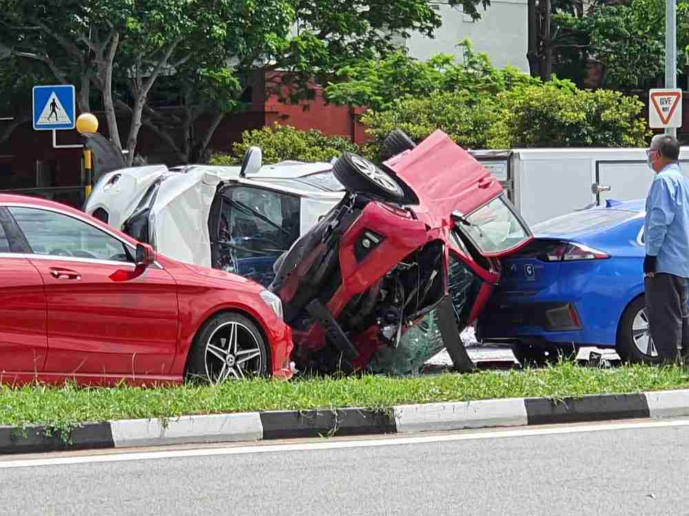 In dashcam videos circulating on private messaging apps, a red car can be seen rear-ending a white car in Singapore. The red car then overturned on the road. u00e2u20acu201d Social media pic via TODAY