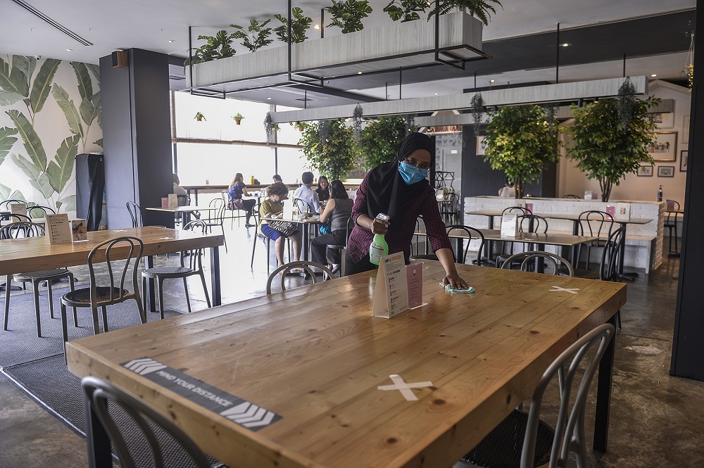 A worker sanitises a table at the Marmalade Cafe in Bangsar Village June 20, 2020. ― Picture by Miera Zulyana