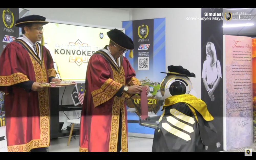 A robot receiving a scroll from UniSZA vice-chancellor Datuk Dr Hassan Basri Awang Mat Dahan (middle). u00e2u20acu201d Screengrab from YouTube/UniSZA Official Channel