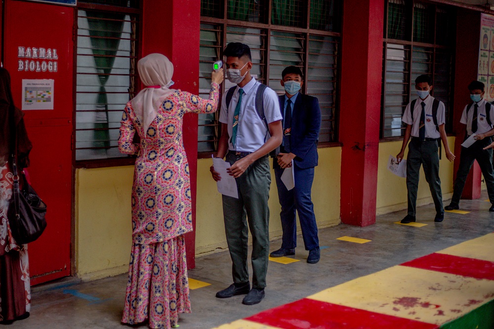 A student gets his temperature checked before entering the classroom at SMK Lembah Keramat Jaya in Kuala Lumpur June 24, 2020. 