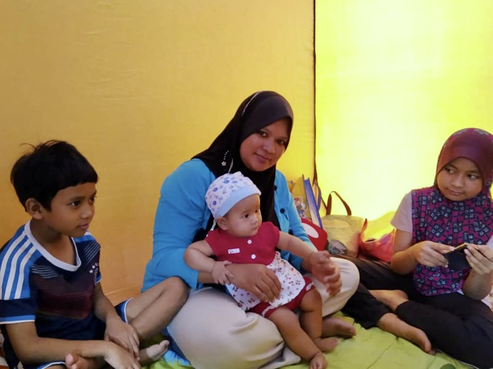 Siti Khadijah Rahman, 38, with her children at SK Kampung Sawah that has been turned into a temporary flood relief centre in the afternoon. u00e2u20acu201d Picture by Ben Tan