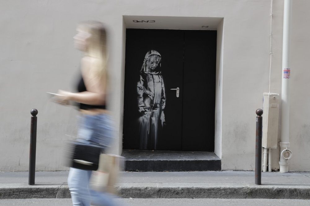 In this file photo, a woman walks past a recent artwork by street artist Banksy in Paris on a street to the Bataclan concert hall where a terrorist attack killed 90 people on November 13, 2015. The stolen Banksy work has been found in Italy. u00e2u20acu201d AFP pic
