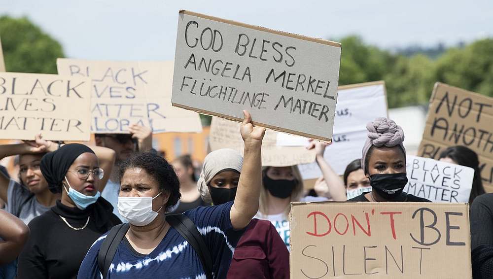 A woman wearing a face mask holds up a placard reading 'God bless Angela Merkel u00e2u20acu201d refugees matter' admid a Black Lives Matter demonstration in Stuttgart, Germany June 13, 2020. u00e2u20acu201d AFP pic