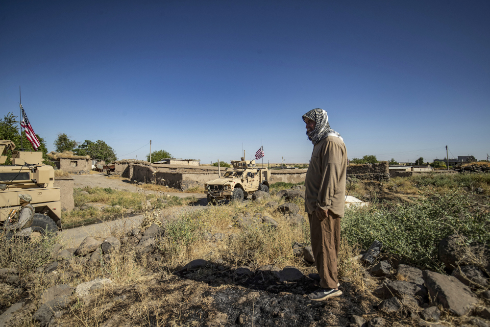 A Syrian man looks at a US military convoy advancing through the western countryside of the north-eastern Syrian town of al-Malikiyah (Derik), as it patrols Kurdish towns near the border with Turkey, June 7, 2020. u00e2u20acu201d AFP pic 