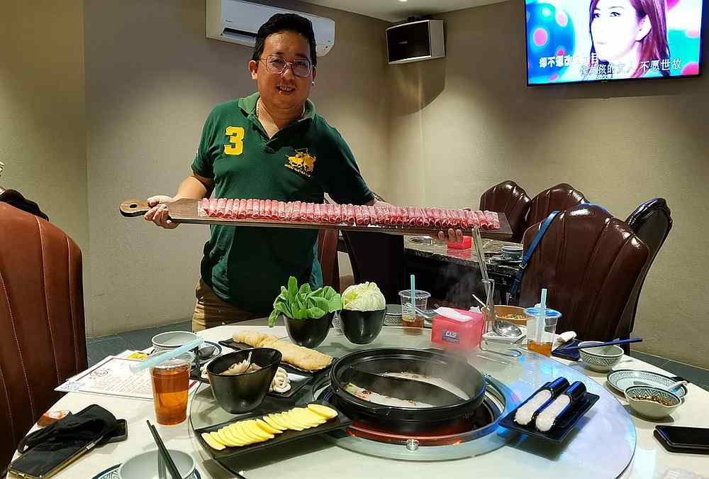 A customer shows off the one-metre long free pork slices from Wo Men Zhe Yi Guo. — Picture via Facebook/Tzeyung Toh