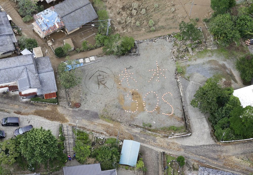 An aerial view shows the words u00e2u20acu02dcRice, Water, SOSu00e2u20acu2122 spelled out on the ground in the flood-ravaged Kuma village, Kumamoto prefecture July 5, 2020. u00e2u20acu201d Kyodo handout via Reuters