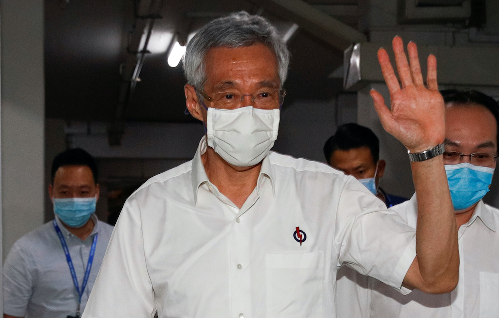 Singapore's Prime Minister Lee Hsien Loong waves as he arrives at a People's Action Party branch office, as ballots are being counted during the general election, in Singapore July 11, 2020. — Reuters pic