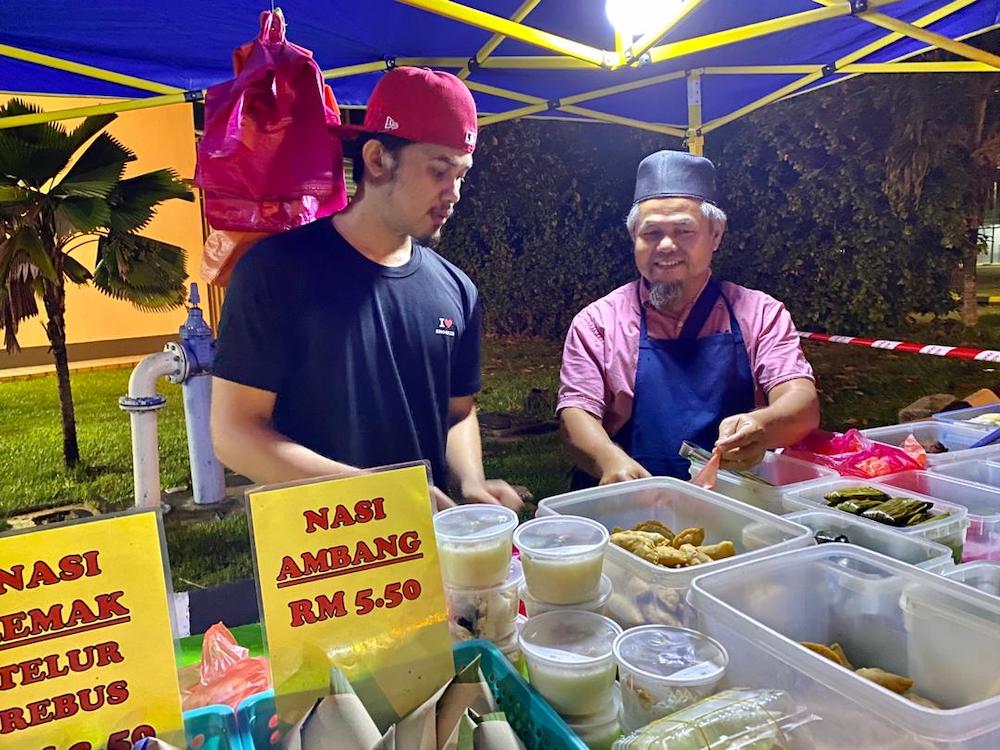 Jasri Amir (right), who has a makeshift food outlet in Taman Perling, has seen his earnings fall by more than half. — Picture by Ben Tan