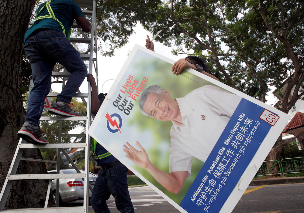 Workers hang up electoral poster for ruling People's Action Party ahead of the general election in Singapore June 30, 2020. u00e2u20acu201d Reuters pic