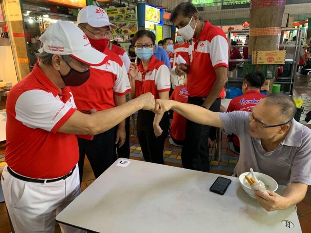Dr Tan Chong Bock fist bumping a resident at Ayer Rajah Market, accompanied by his West Coast GRC team, on July 12, 2020. nu00e2u20acu201du00c2u00a0TODAY pic