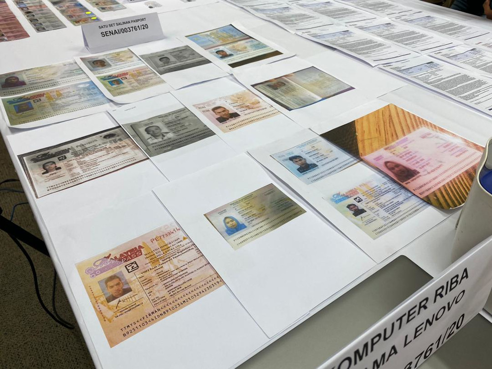 Copies of the forged Indonesian passports, Malaysian Immigration i-Cards and Covid-19/SARS-CoV-2 medical examination certificates from a private hospital were among documents seized during an Immigration raid in Johor July 20, 2020. — Picture by Ben Tan