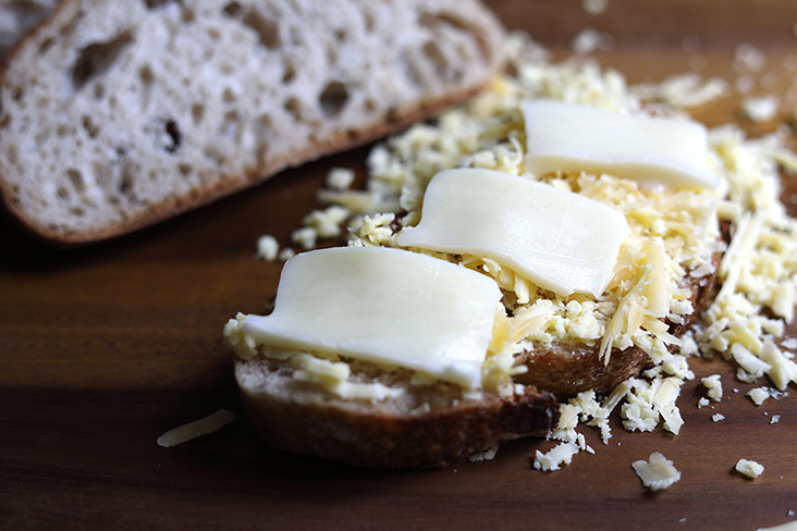 Layer grated and sliced cheeses on your slices of bread.