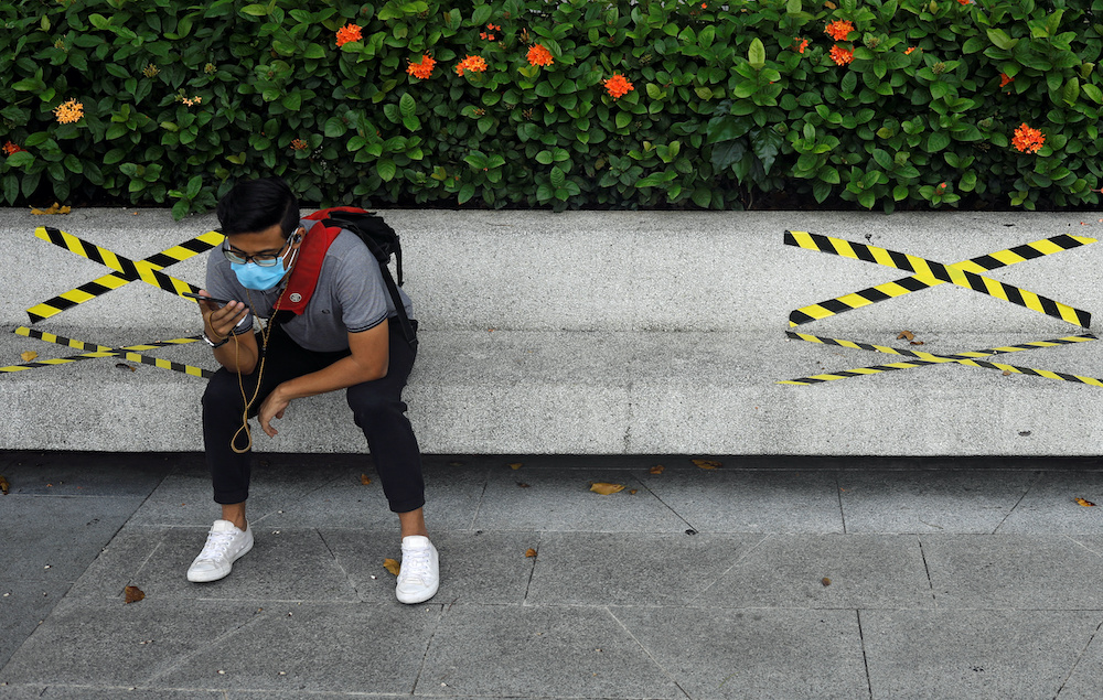 A man sits on a bench with distance markers along Marina Bay, amid the coronavirus disease outbreak, in Singapore July 14, 2020. u00e2u20acu201d Reuters picnnn