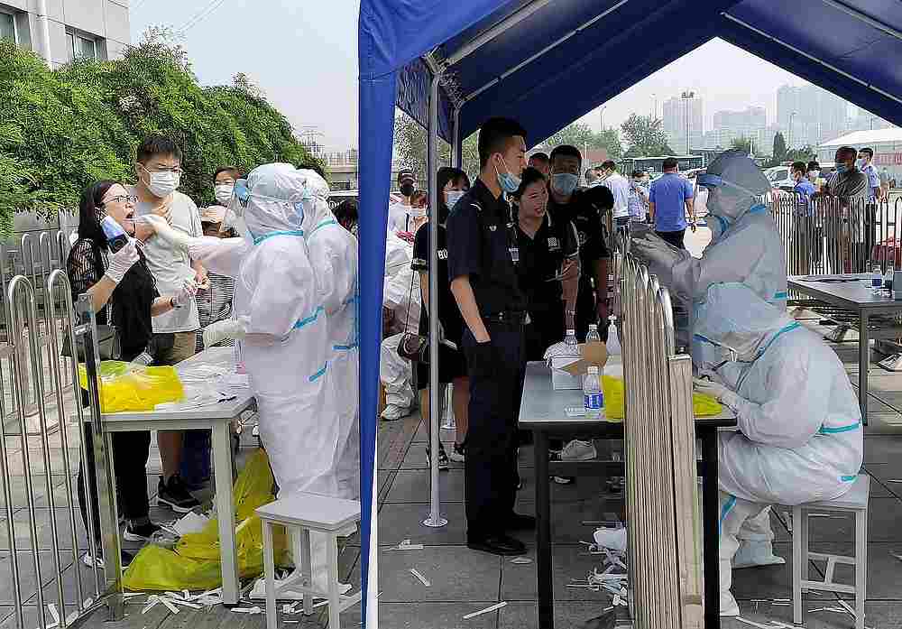 People line up at a testing site where medical workers in protective suits collect swabs for nucleic acid tests, after new cases of Covid-19 were confirmed in Dalian, Liaoning province, China July 24, 2020. u00e2u20acu201d China Daily pic via Reuters
