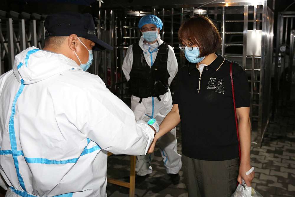 A worker in protective suit measures the body temperature of a woman at the entrance to a residential compound, following the Covid-19 outbreak in Urumqi, Xinjiang in China July 28, 2020. u00e2u20acu201d cnsphoto via Reuters