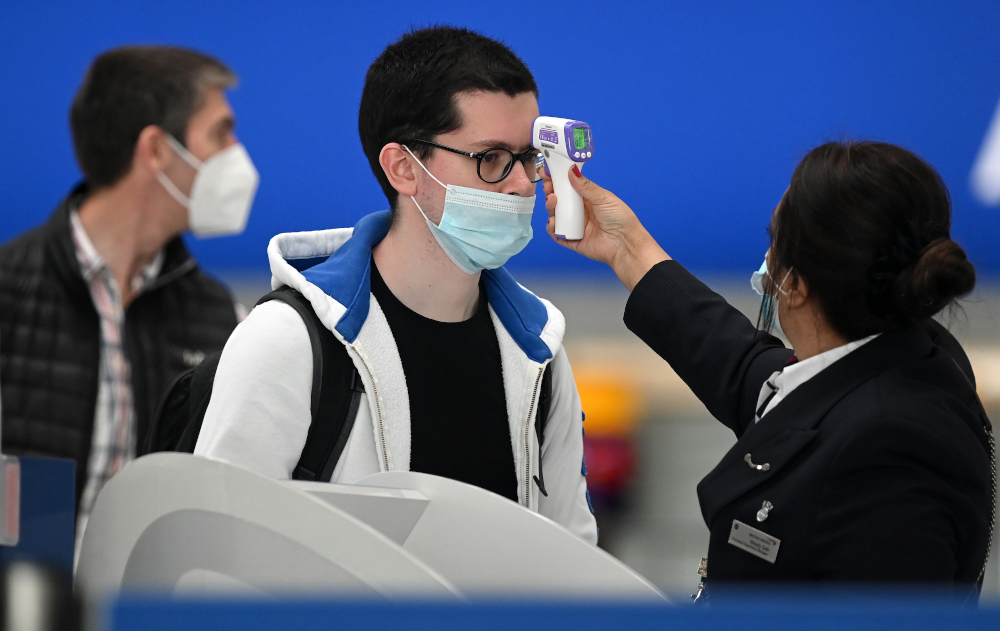 In this file photo taken July 10, 2020, passengers wearing face masks have their temperature taken at a British Airways check-in desk at Heathrow airport, west London. u00e2u20acu201d AFP pic 