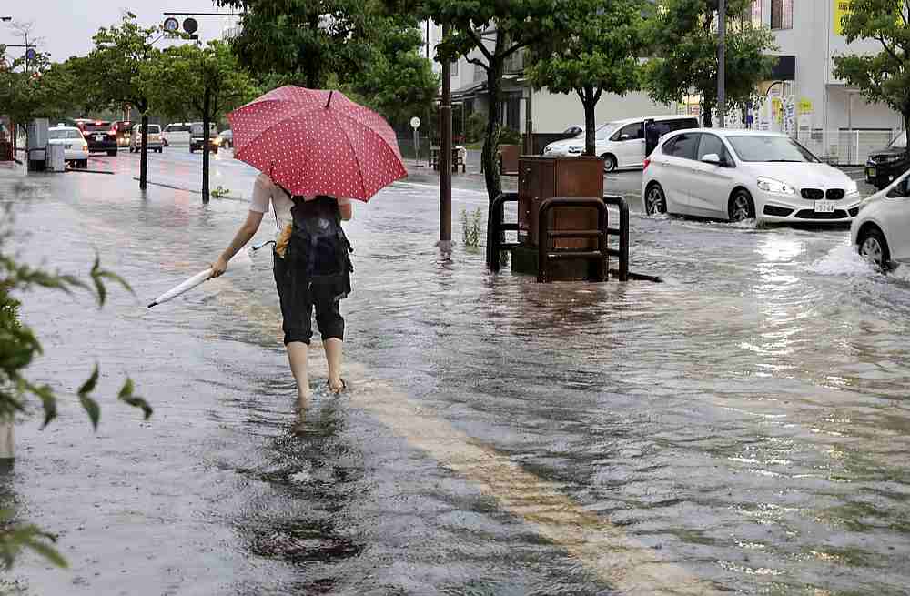 A person walks in a flooded street near a railway station in Saga, Japan July 6, 2020. u00e2u20acu201d Kyodo pic via Reuters