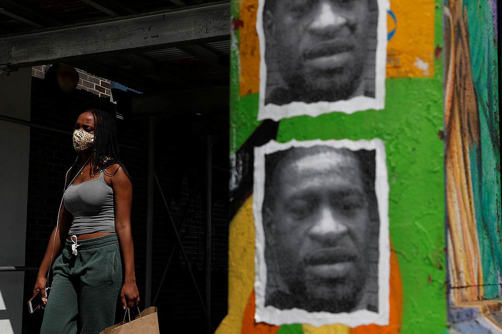 A woman walks with a protective face covering past a mural of George Floyd along 125th street in the Harlem neighborhood of New York July 9, 2020. u00e2u20acu201d Reuters pic
