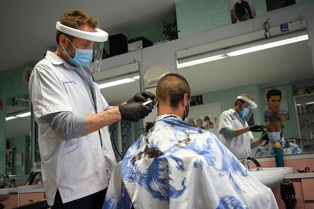 A hairdresser wearing a protective face mask and plastic gloves cuts the hair of a customer at Giaquinto hair salon after Switzerland started to ease the restrictions imposed. u00e2u20acu201d AFP pic 