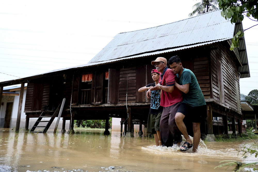 Muhammad Nur Zharfan Rusidi (right) helps his grandfather Wahab Rashid while being assisted by his aunt Salmi Wahab during a flash flood in Kampung Bemban Seremban July 13, 2020. u00e2u20acu201d Bernama pic