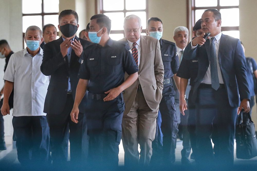 Datuk Seri Najib Razak (centre) is escorted by police officers at the Kuala Lumpur Court Complex July 28, 2020. u00e2u20acu2022 Picture by Ahmad Zamzahuri
