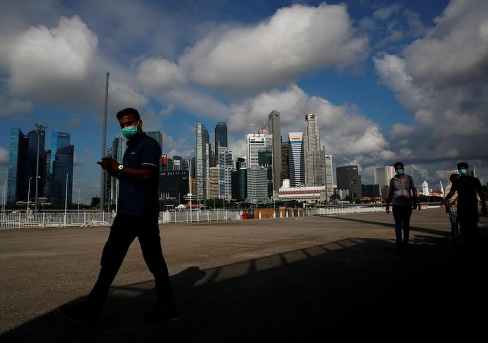 Essential workers wearing face masks walk past the skyline of the central business district outside a regional screening centre amid the coronavirus disease (Covid-19) outbreak in Singapore June 9, 2020. u00e2u20acu201d Reuters pic