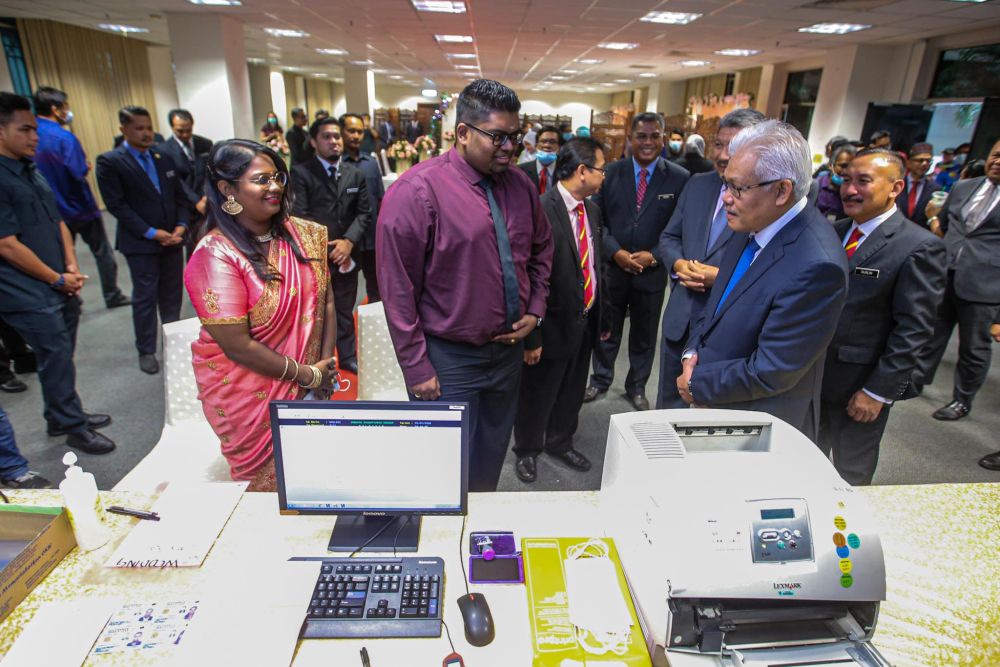 Home Minister Datuk Seri Hamzah Zainudin speaks to  Indian couple Silambarasaan Machan (centre) and Tinakary Pannir Selvam (left) at the National Registration Department in Putrajaya July 20, 2020. — Picture by Hari Anggara
