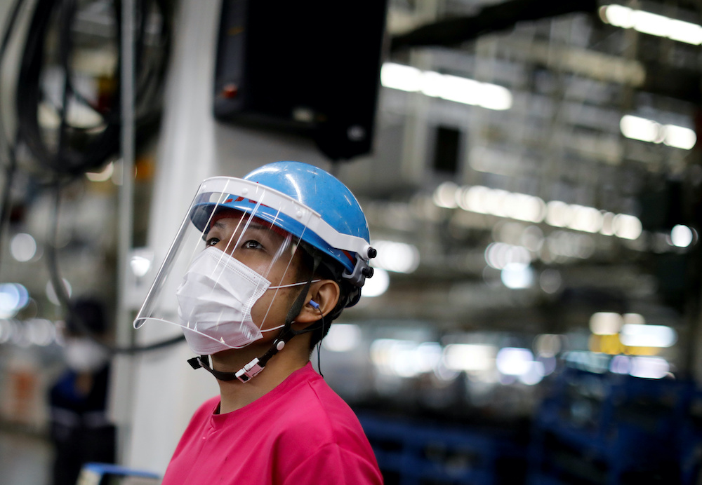 An employee wearing a protective face mask and face guard works on the automobile assembly line at Kawasaki factory of Mitsubishi Fuso Truck and Bus Corp in Kawasaki Japan May 18, 2020. u00e2u20acu201d Reuters pic