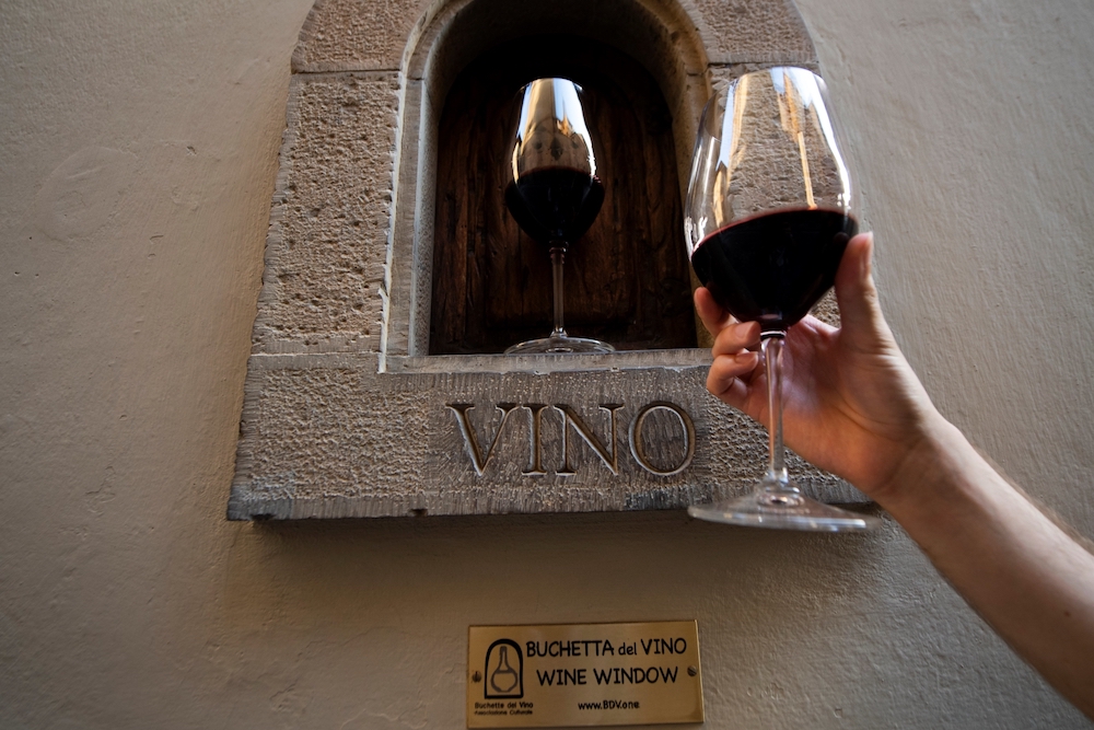 A person holds a glass of wine next to a u00e2u20acu02dcbuchetta del vinou00e2u20acu2122. u00e2u20acu201d AFP pic